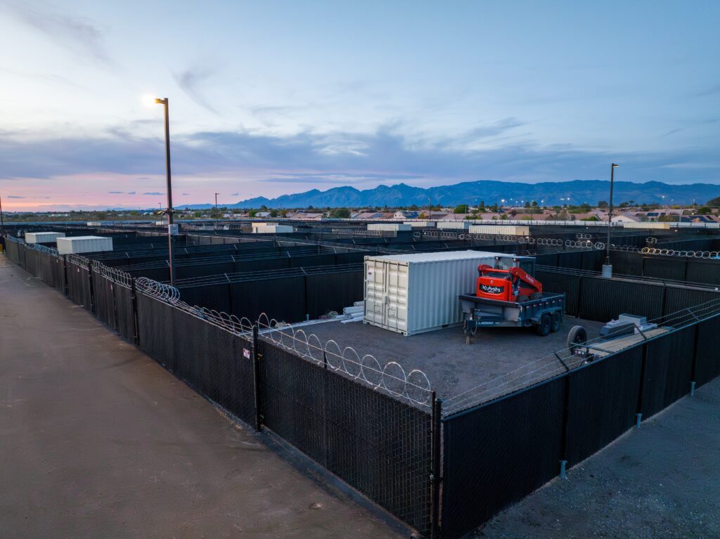 Storage Yard filled with a storage container, trailer, and equipment at dusk